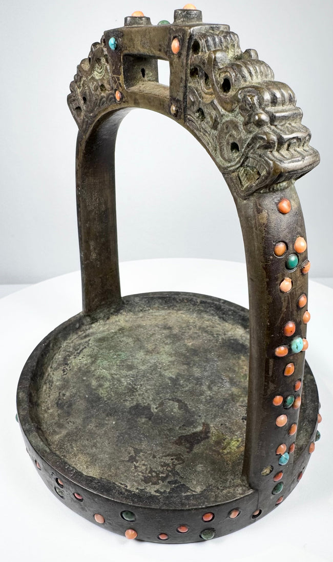 Asian ceremonial horse stirrup with dragon-head terminals, broad footplate, and mixed coral, turquoise, and glass decoration.