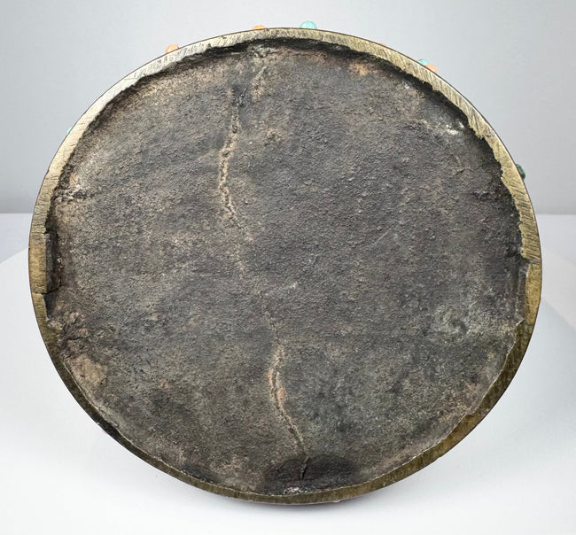 Underside of an 18th–19th century Mongolian or Tibetan bronze stirrup, showing the broad circular footplate, dark aged surface, bronze rim, and traces of turquoise and coral inlay around the edge.