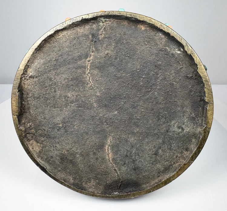 Underside of an 18th–19th century Mongolian or Tibetan bronze stirrup, showing the broad circular footplate, dark aged surface, bronze rim, and traces of turquoise and coral inlay around the edge.
