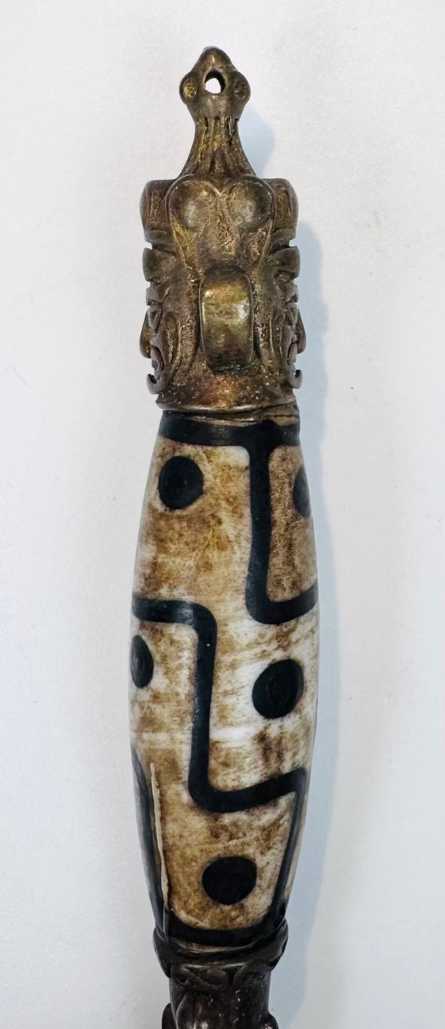 Side view of Himalayan phurba amulet with elongated patterned bead and pointed blade