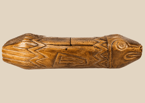 Full side view of hand-carved Melanesian wooden fish drum showing detailed incised patterns