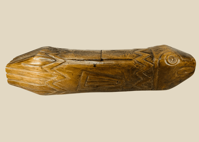 Full side view of hand-carved Melanesian wooden fish drum showing detailed incised patterns