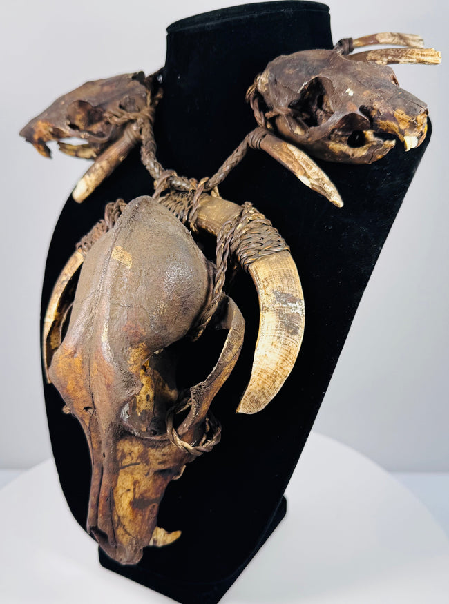 Animal skull necklace highlighting the central skull’s elongated muzzle, open eye socket, and surrounding twine bindings.