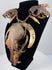 Animal skull necklace highlighting the central skull’s elongated muzzle, open eye socket, and surrounding twine bindings.