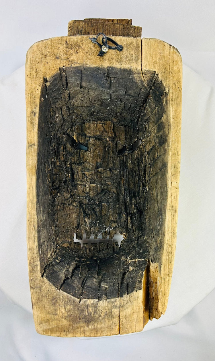 Reverse view of carved mask showing hollowed interior and attachment marks from traditional use or mounting.