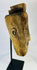 Angled side view of carved tribal mask highlighting expressive grimace, worn patina, and traces of soot from ritual use.