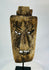 Close-up of facial details on hardwood mask revealing carved teeth, brow ridges, and surface fissures.