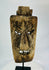 Close-up of facial details on hardwood mask revealing carved teeth, brow ridges, and surface fissures.