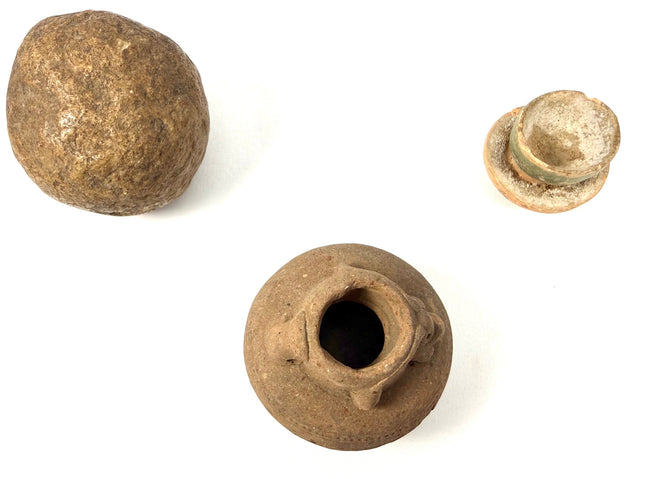 Trio of ancient artifacts: stone sphere, glazed stopper, and clay vessel