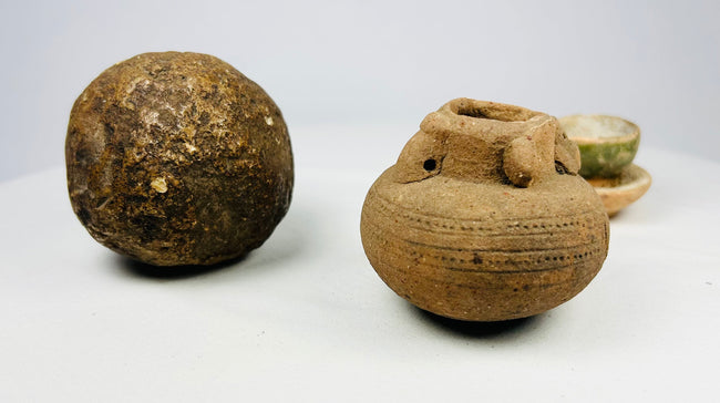 Three-piece antiquities grouping: spherical stone tool, miniature terracotta jar, and green-glazed ceremonial cup.