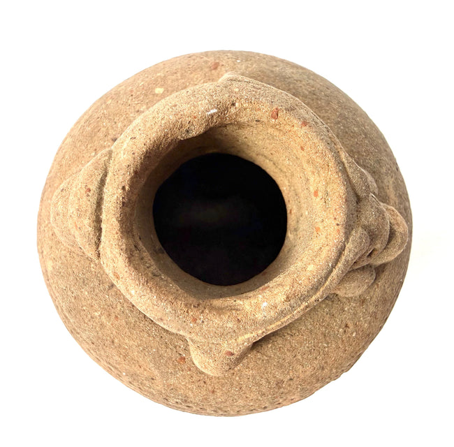 Top-down view into dark opening of ancient clay vessel with rolled rim
