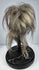 Handcrafted shrunken head-style display object in stitched animal hide with horse hair and museum-style glass presentation.