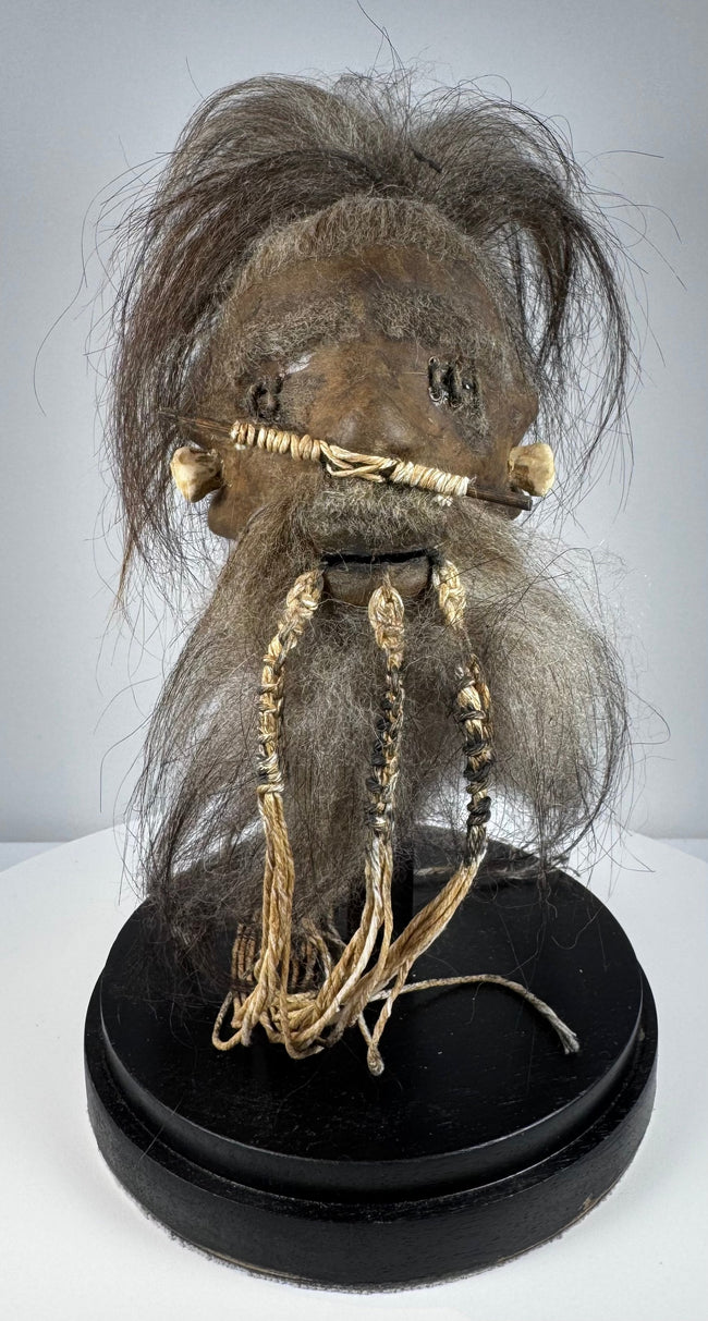 Mid-20th-century Amazonian-style shrunken head replica crafted from stitched animal hide with horse hair and preserved in a glass globe.