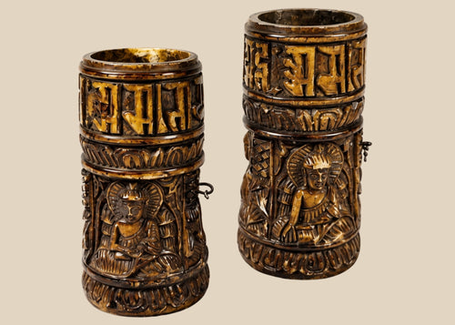 Pair of small Tibetan Buddhist prayer wheels carved from human femur bone, each 3.1 in tall, featuring three relief Buddha figures and a band of Sanskrit inscriptions, used for ritual prayer and meditation.