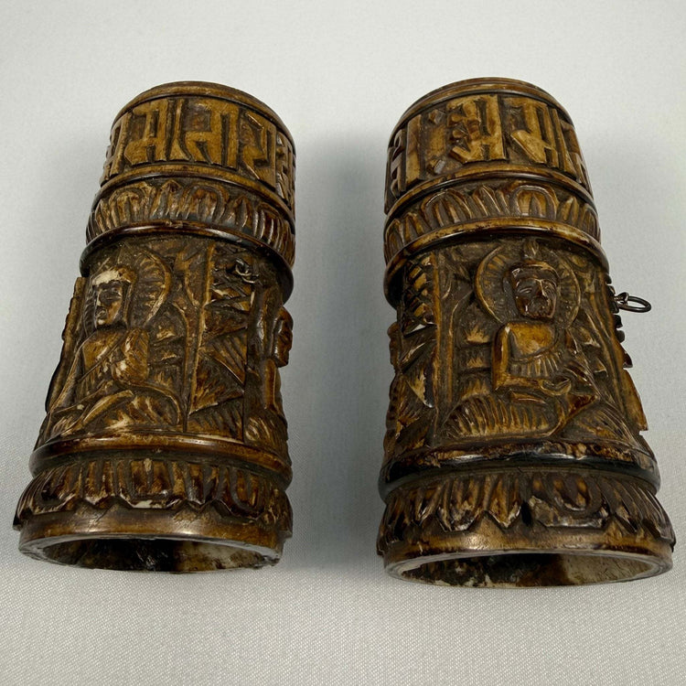 Tibetan Buddhist devotional prayer wheel with carved Buddha figures and sacred inscriptions