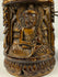 Close view of hand-carved Tibetan prayer wheel showing Buddha figures in raised relief