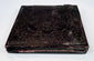 Antique cased photograph with ornate dark embossed exterior, decorative border, and age-related patina
