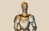 Victorian-era full suit of armor, early 19th century, 80 inches tall by 32 inches wide. Acid-etched metal plates decorated with intricate engravings of mythical creatures, dragons, crowns, battle scenes, and scrolling foliage. Inspired by 15th-century medieval armor, reflecting Victorian fascination with chivalric ideals and Gothic artistry. Mounted on a custom wooden display stand.