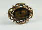 Close-up of aged patina on a gold-plated Victorian mourning brooch frame.