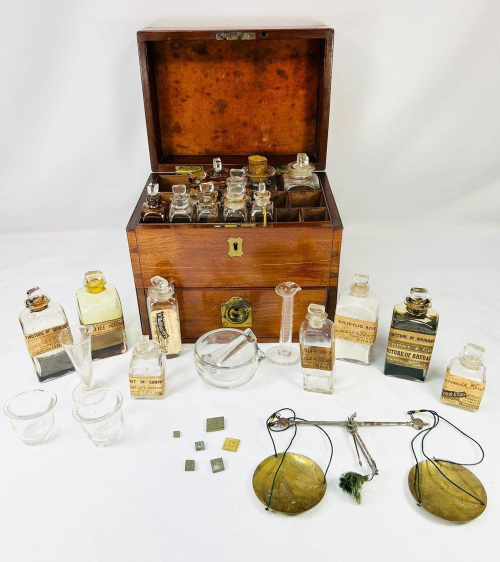 Antique Victorian apothecary box crafted in mahogany with brass fittings, containing original glass bottles with labels, balance scales, mortar and pestle, and chemist’s tools, late 19th century.