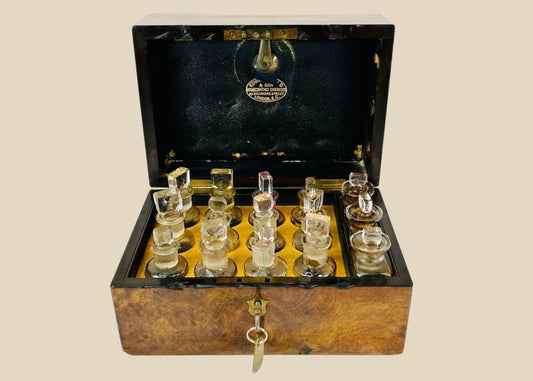 Victorian apothecary box by Edward Gould & Son, London, late 19th century. Burl wood case with brass fittings, velvet-lined interior, and twelve original labeled glass bottles with stoppers, including Arnica Montana, Belladonna, and Bryonia Alba. Reflects Victorian homeopathy, craftsmanship, and medical history.