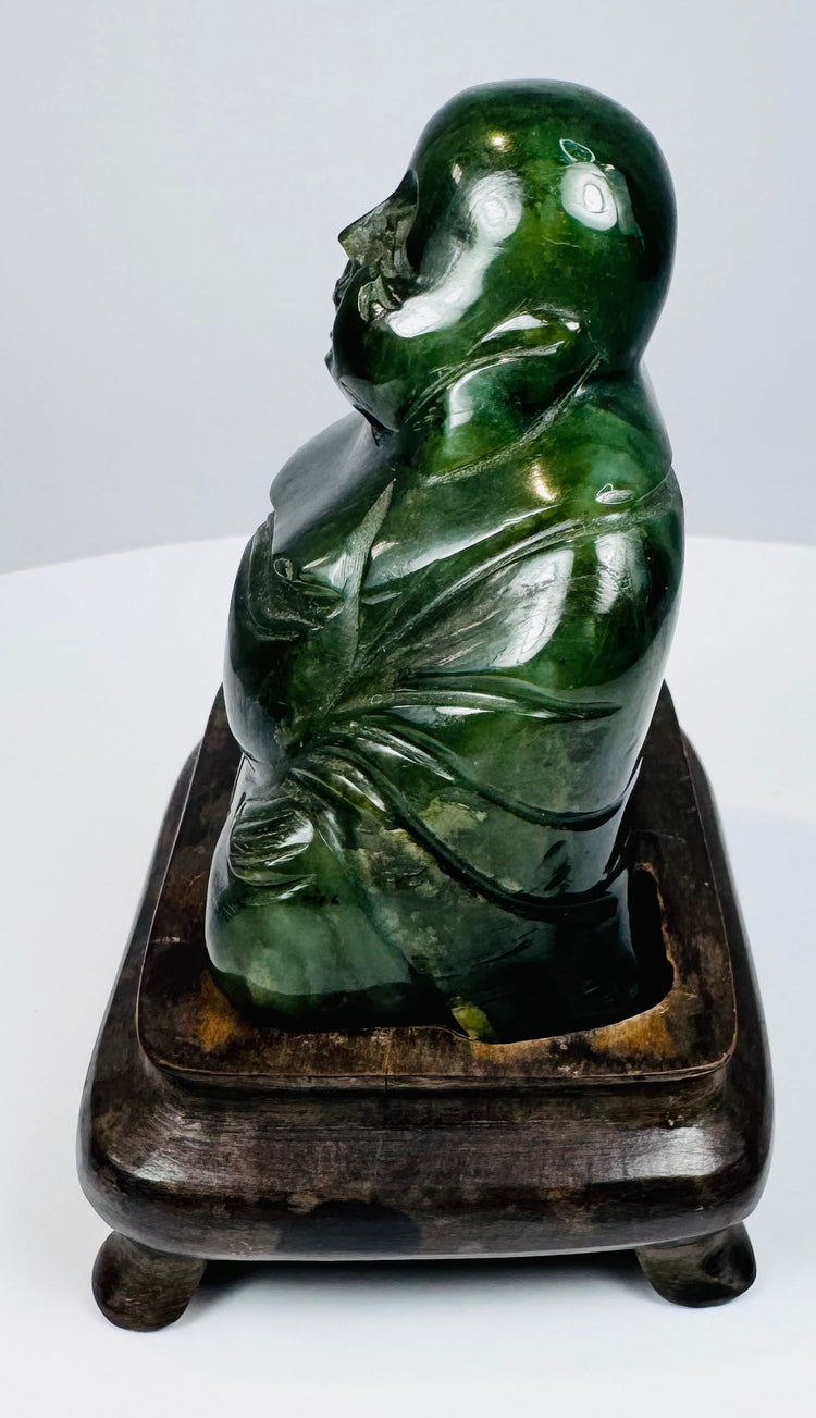 Side profile of Chinese dark green hardstone Laughing Buddha sculpture on fitted wooden stand