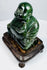 Angled view of Chinese carved hardstone Budai statue with polished green stone and hardwood base
