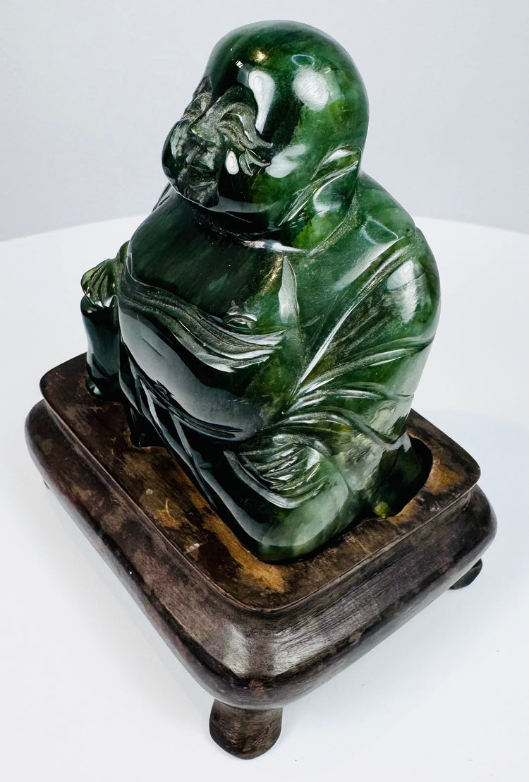 Angled view of Chinese carved hardstone Budai statue with polished green stone and hardwood base