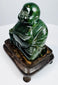 Angled view of Chinese carved hardstone Budai statue with polished green stone and hardwood base