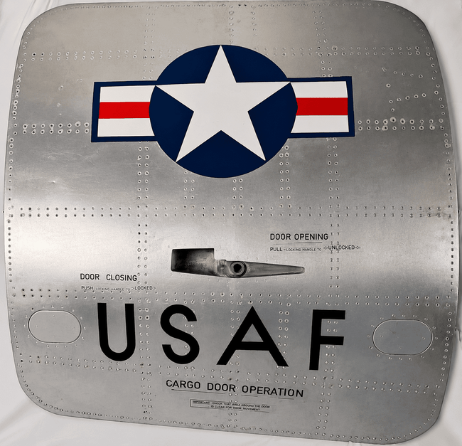 Front view of a vintage USAF Boeing 737 cargo door with military roundel, riveted aluminum skin and original stenciling