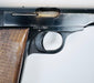 Close-up of the FN Browning Model 1922’s ejection port, curved trigger, and worn steel beside the walnut grip.