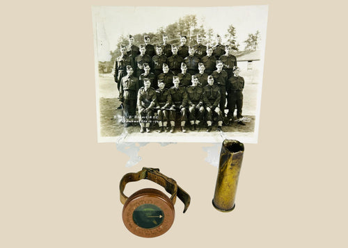 Vintage WWI military memorabilia set including a soldier’s wrist compass, a spent shell casing, and a sepia-toned unit photograph of troops, displayed on a white background.