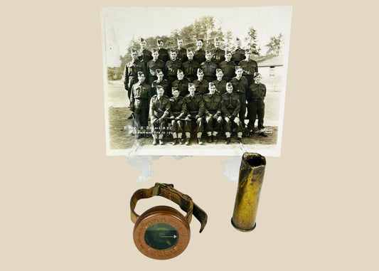 Vintage WWI military memorabilia set including a soldier’s wrist compass, a spent shell casing, and a sepia-toned unit photograph of troops, displayed on a white background.