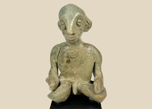 Hand-modeled West Mexican Nayarit Chinesco terracotta figure of a seated male with slit eyes, pinched nose, cross-legged pose, and red/orange pigment remnants, featuring earthen and mineral accretions, mounted on a modern wood display block, ca. 100 BCE–300 CE