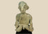 Hand-modeled West Mexican Nayarit Chinesco terracotta figure of a seated male with slit eyes, pinched nose, cross-legged pose, and red/orange pigment remnants, featuring earthen and mineral accretions, mounted on a modern wood display block, ca. 100 BCE–300 CE