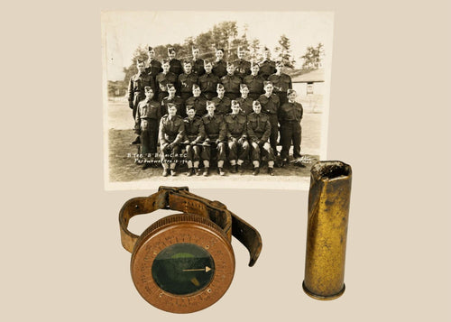 Vintage WWI military memorabilia set including a soldier’s wrist compass, a spent shell casing, and a sepia-toned unit photograph of troops, displayed on a white background.