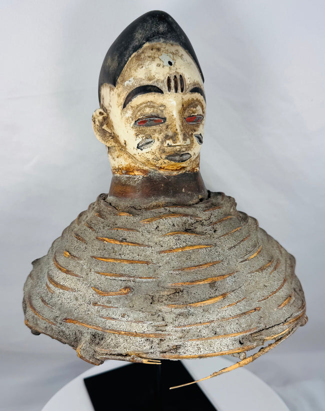 Mid-20th century Yoruba Egungun ceremonial headdress with white-painted face, red eyes, and woven fiber structure.