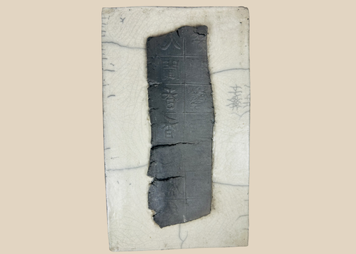 Ancient Chinese inscribed ceramic fragment mounted on backing with grid pattern and stylized characters