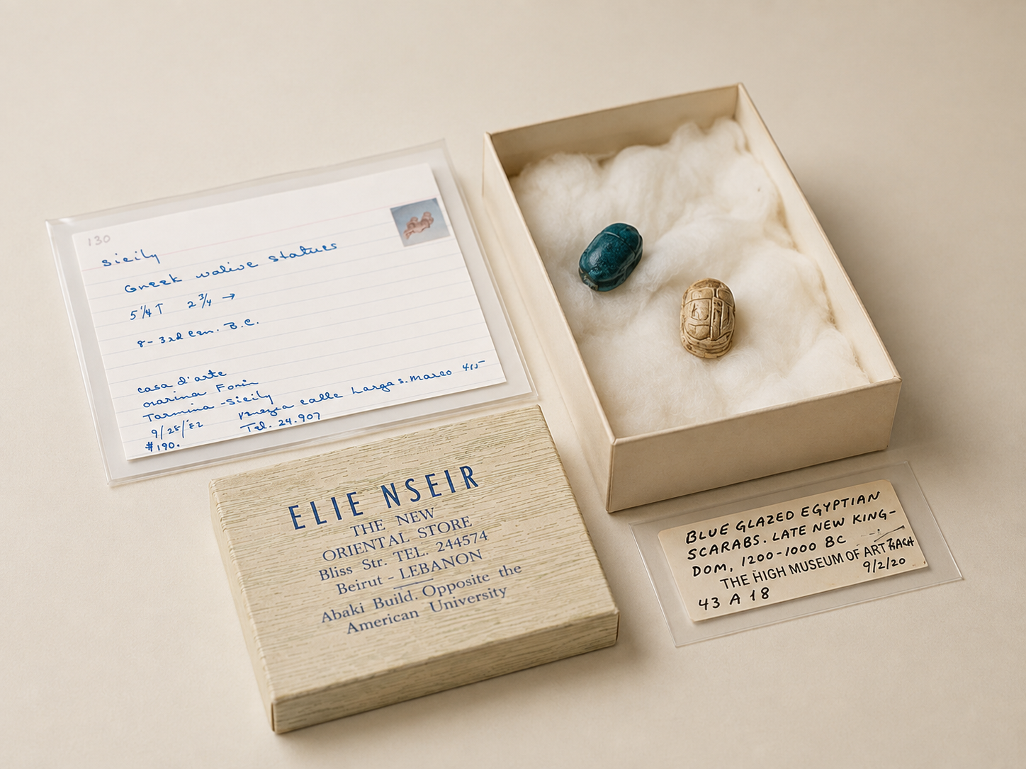Two ancient Egyptian scarabs stored in a padded archival box beside their original provenance cards, labels and collection documentation.