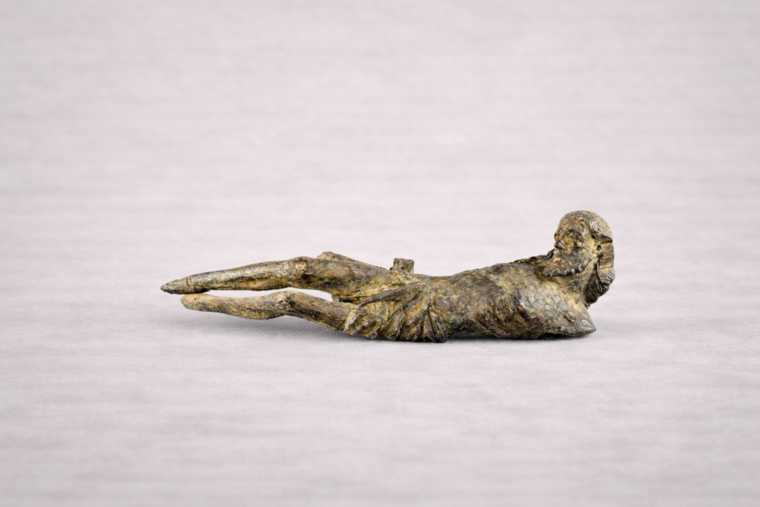 Antique wooden reclining figure of Jesus Christ, devotional religious sculpture displayed on neutral background