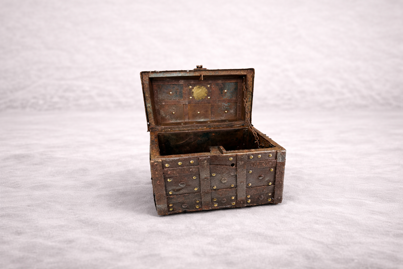 Antique iron-bound treasure chest with riveted panels and open lid, rustic patinated metal box displayed on neutral background