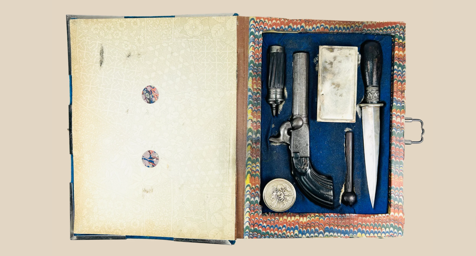 19th-century Continental concealed gentleman’s defense set in fitted case, including pistol, dagger, and accessories on beige background