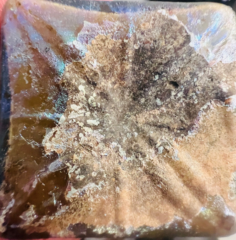 Close-up of iridescent surface on an Early Imperial Roman glass bottle showing mineral weathering and shimmering patina, 1st century CE.