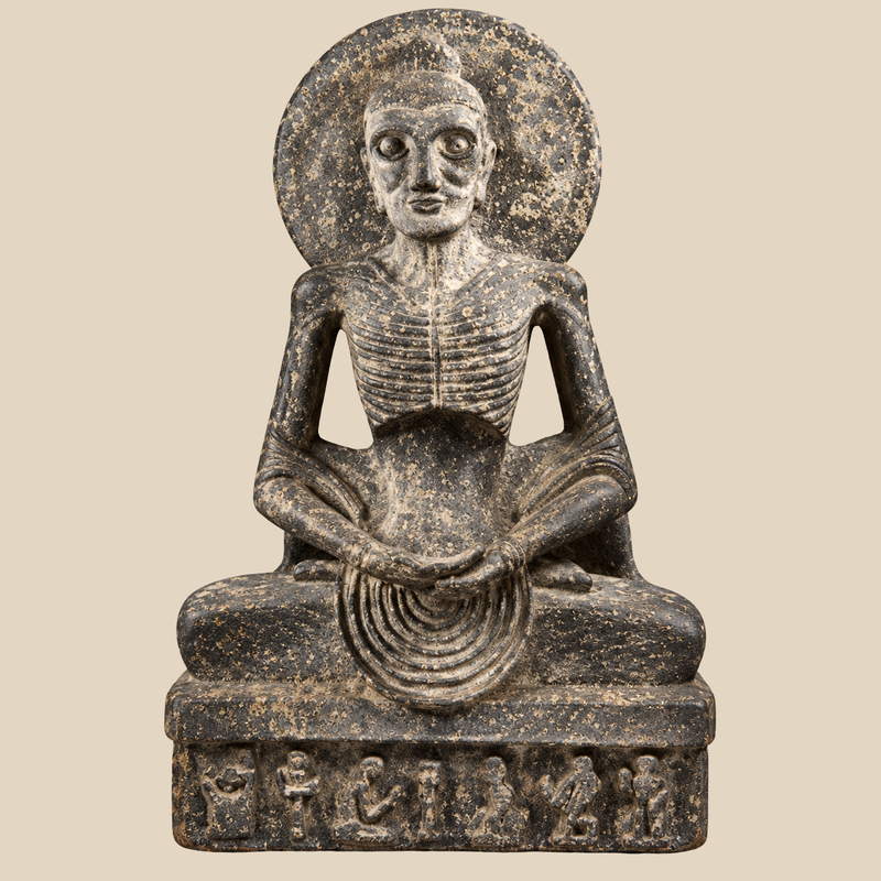 Dark Egyptian-style seated figure with a circular disk, wide eyes, ribbed chest, crossed legs, clasped hands and carved symbols along the rectangular base.