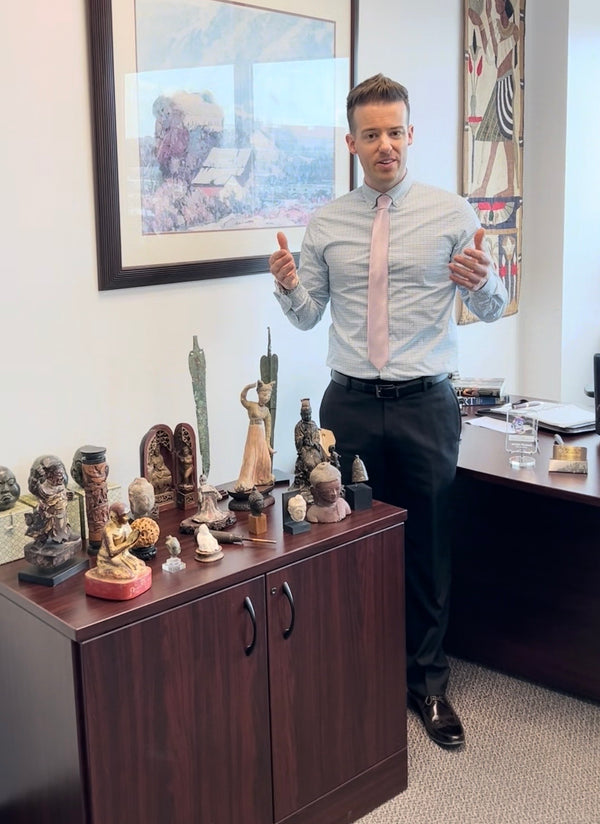 Jordan Thomas, Founder and Head Curator of Relic & Rarity, standing beside a display of authentic historical artifacts in the company's Markham, Ontario office, highlighting the gallery's expertise in sourcing, researching, authenticating, and preserving museum-quality antiquities from around the world.