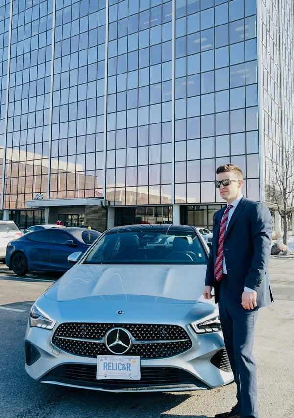 Jordan Thomas of Relic & Rarity standing beside a Mercedes-Benz in front of a modern glass building in Markham, Ontario.