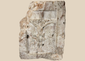 Medieval carved stone fragment depicting Christ on the Cross within an architectural niche with surrounding relief details