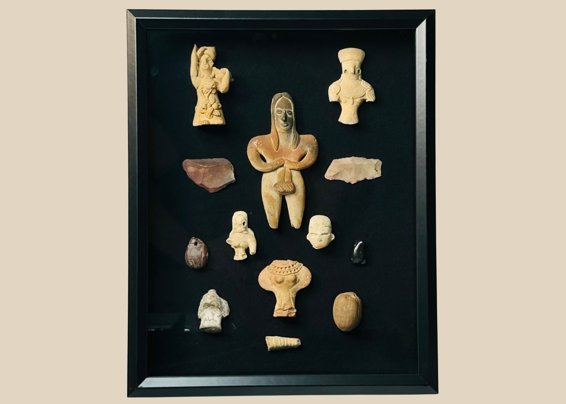 Framed collection of Pre-Columbian terracotta and stone artifacts displayed in a shadowbox.