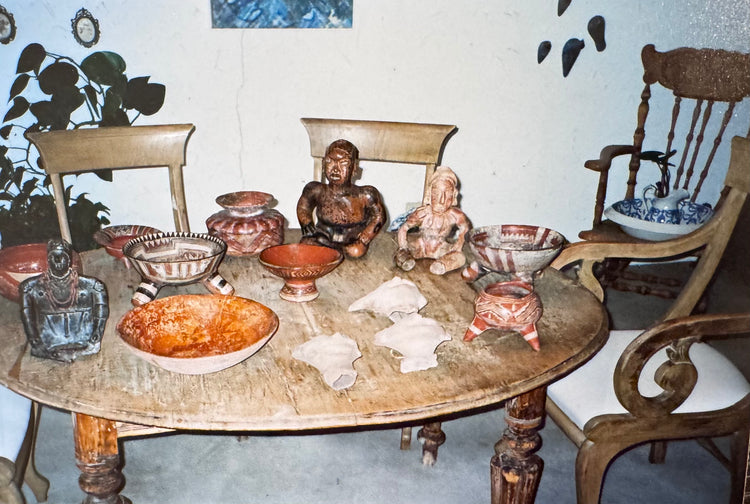 Archival collection photograph showing Pre-Columbian terracotta figures, Sonriente heads, ceramic vessels, and a West Mexican tripod bowl displayed together.