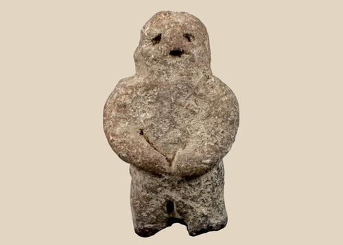 Pre-Columbian carved stone standing figure with folded arms and deeply recessed eyes